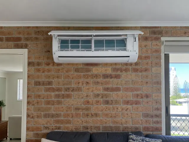Clean split system indoor head on brick wall with open front panel and visible filters in a living room in Coolangatta
